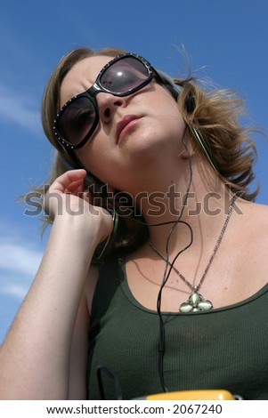 a young woman enjoys music on a old cassette radio with head phones outside