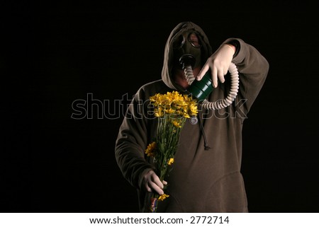 a man in a gas mask holds the filter to flowers in an attempt to smell them