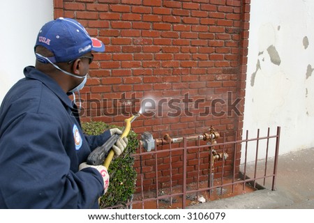 an unidentifiable person cleans graffiti off a wall in the Urban Jungle called  Los Angeles