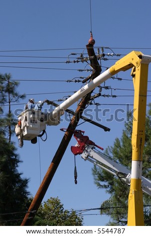Workers in a man lift aka bucket lift prepare to remove and replace a 95 foot utility pole broken by a car accident