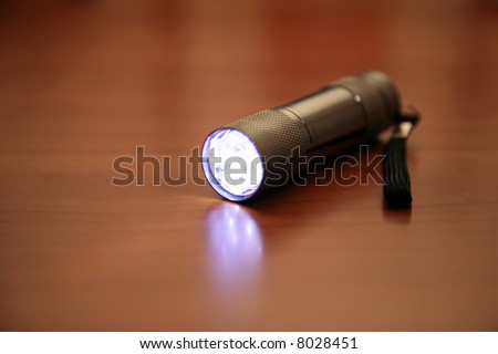 a Mulit Bulb LED flashlight lays on a table emitting bright light while turned on