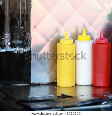 condiments of mustard, mayonnaise, ketchup and hot sauce on a hot dog cart for your use