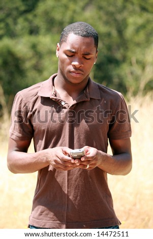a handsome african american man thinks and responds while he text messages on his cell phone