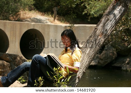 a young woman reads a book outside
