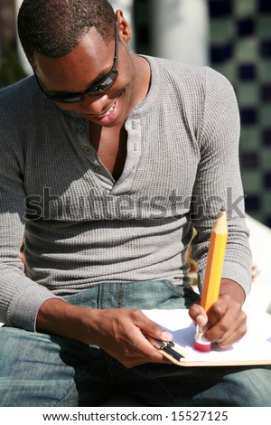 a young man takes notes and erases mistakes on a sheet of paper with a giant pencil