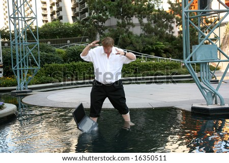 Computer damage concepts a business man is upset as he realizes that he just dropped his laptop in a pool of water
