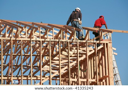 unidentifiable construction workers work on framing a building