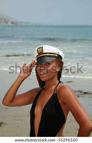a beautiful young african american woman wears a sea captains hat while enjoying a day at the beach