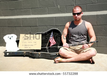 a young man plays music for tips outside