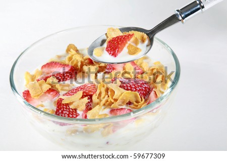 a clear glass bowl of corn flakes with strawberries and milk