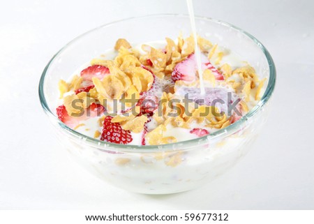 a clear glass bowl of corn flakes with strawberries and milk