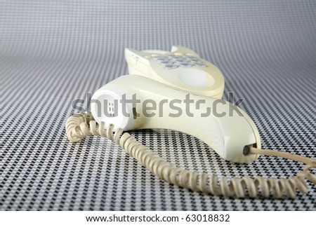an old generic cream colored analog telephone sits on a black and white background waiting for someone to 