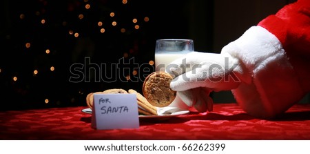 Santa Claus takes a cookie left out for him on Christmas Eve as a thank you gift for leaving presents to a grateful boy or girl