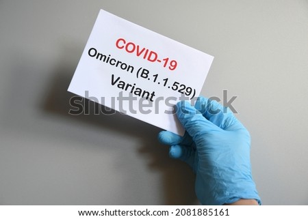 Doctor's hand in blue glove with white paper and text Covid-19 Omicron Variant. Concept of medical variety Omicron variant and COVID-19. COVID-19 omicron variant concept.