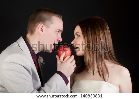 young lovers woman and man biting an apple simultaneously