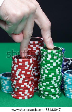 Men\'s fingers are marching up the pile of playing chips