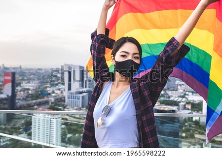 LGBT, portrait of lesbian couple Asian women using lips kissing under rainbow cloth,lesbian concepts.Two pretty women of different race play wrapping in a rainbow flag
