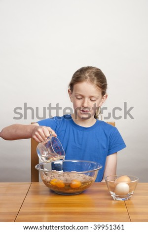 young girl pouring cooking oil into bowl of cake batter