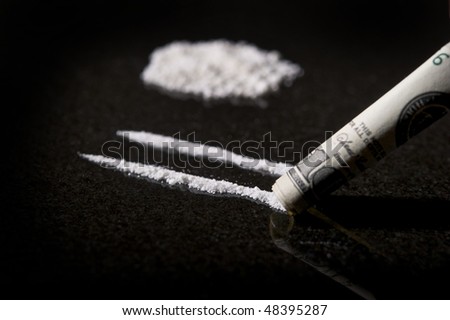 Close up image of lines of cocaine with rolled bill