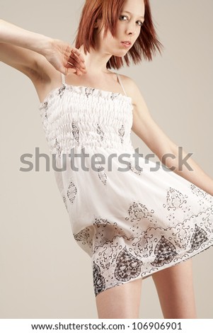 Beautiful young woman in flowing white summer dress with red hair