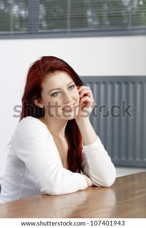 Beautiful young woman resting on a coffee table in front of sofa at home.