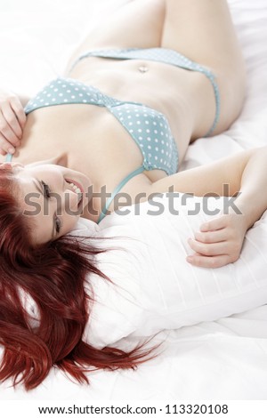 Beautiful young woman resting on her bed at home in her underwear