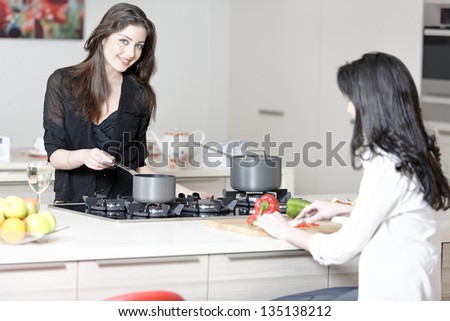 Two friends in a kitchen catching up preparing dinner.