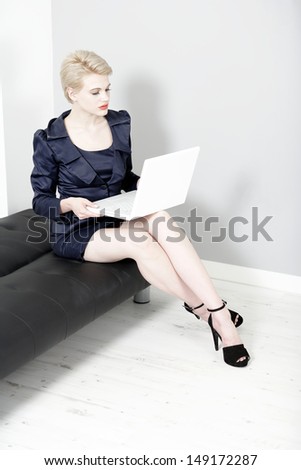 Beautiful young woman working on laptop in a smart business suit.