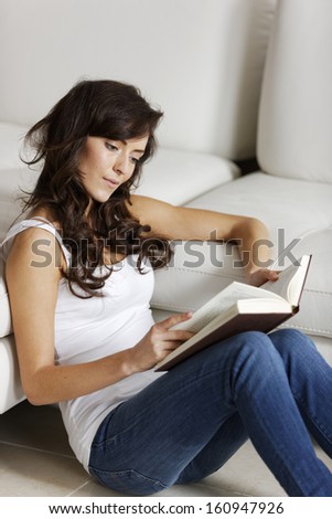 Young woman enjoying a good book in her living room.