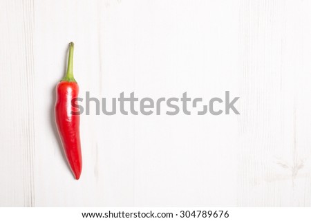Fresh red chilli on a light wooden kitchen work surface