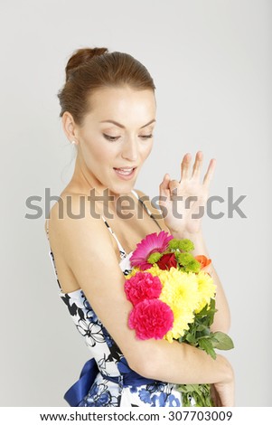 Beautiful young woman in a summer dress holding a fresh bouquet of flowers smiling