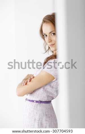 Attractive young woman in a purple dress leaning against a wall waiting for an appointment