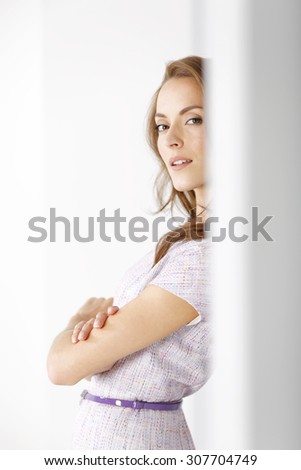 Attractive young woman in a purple dress leaning against a wall waiting for an appointment