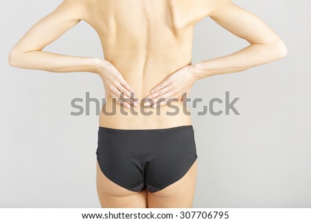 Young woman facing away massaging her lower back from an ache or pain