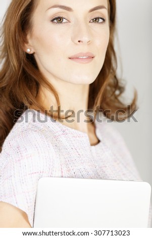 Young woman holding a closed laptop waiting for an appointment in a smart purple dress