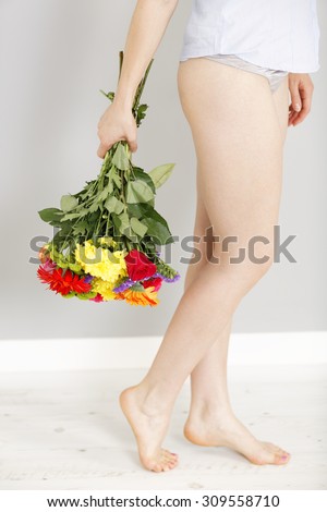 Detail view of a fresh bouquet of flowers being held next to a woman legs in underwear