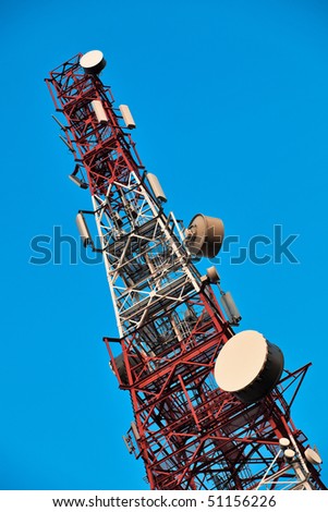 Telecommunication tower with antennas over blue sky.