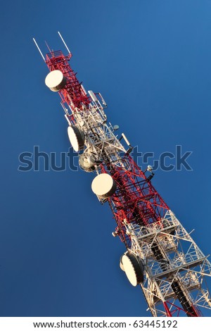 Telecommunication mast with microwave link antennas over a blue sky.