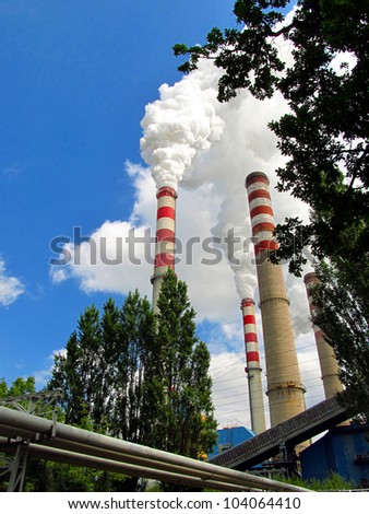 tall chimneys flues of large amounts of steam against a blue sky
