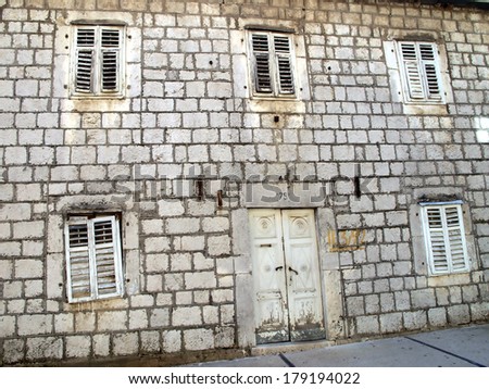 old gray wall with destroyed windows and doors as background