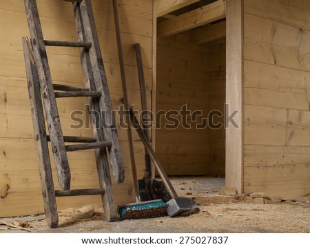 big hammer, broken wooden ladder, shovel and brush in a wooden house built