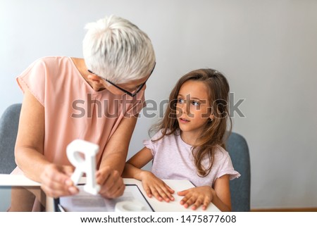 Proper articulation therapy for girl. Stuttering girl and speech therapist. Senior female speech therapist helping a young patient. Repeat after me.. Session with alphabet learning Stok fotoğraf © 