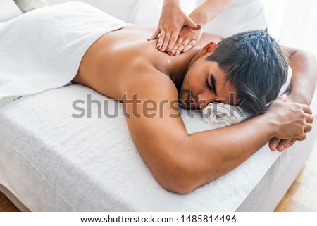 Man having massage in spa salon, closeup. Sports massage. Massage therapist massaging shoulders of a male athlete, working with Trapezius muscle. Young Man Enjoying Massage At Spa