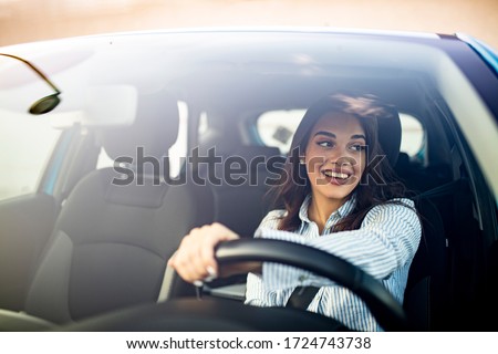Happy woman driving a car and smiling. Cute young success happy brunette woman is driving a car. Portrait of happy female driver steering car with safety belt Stock foto © 