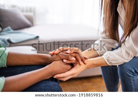 Close-up of psychiatrist hands together holding palm of her patient. Hands of woman reassuring her colleague. Diverse women. African american family couple holding hands