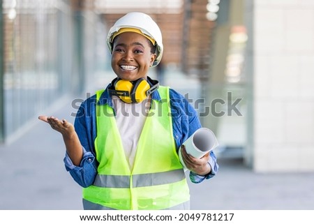 A female architect posing and looking at camera. Portrait of architect standing at building site and looking at camera with copy space. Female construction engineer.  Stockfoto © 