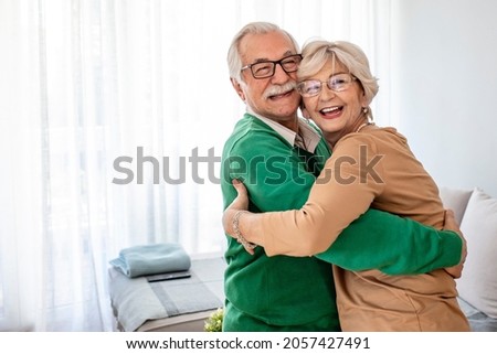 Playful senior husband and wife having fun, celebrating, dancing and laughing together in living room. Senior couple in love dancing at home. Two people, senior couple dancing together in nursing home