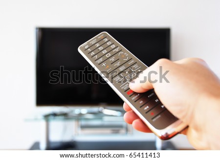 stock-photo-remote-control-in-the-hand-against-tv-screen-65411413.jpg