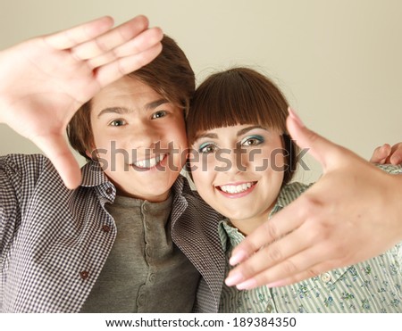 Portrait of attractive couple making frame from fingers and looking through it at camera