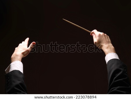 Concert conductor&amp;#39;s hands with a baton isolated on a black background